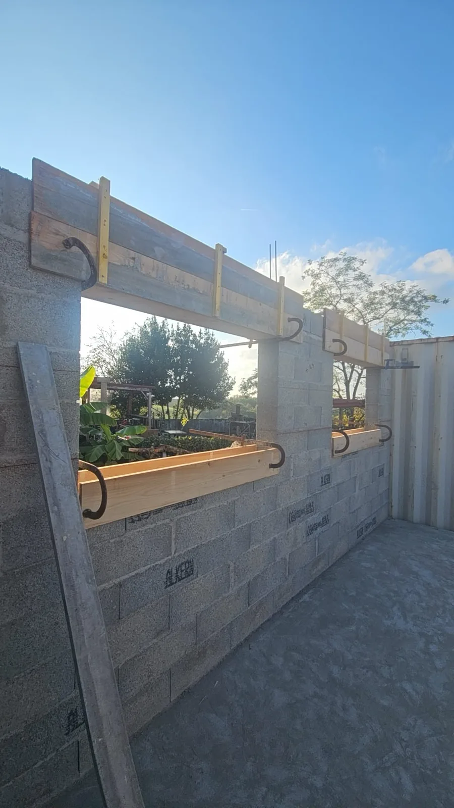 Mur en parpaings avec ouvertures de fenêtres et coffrages bois des linteaux sur un chantier de maçonnerie