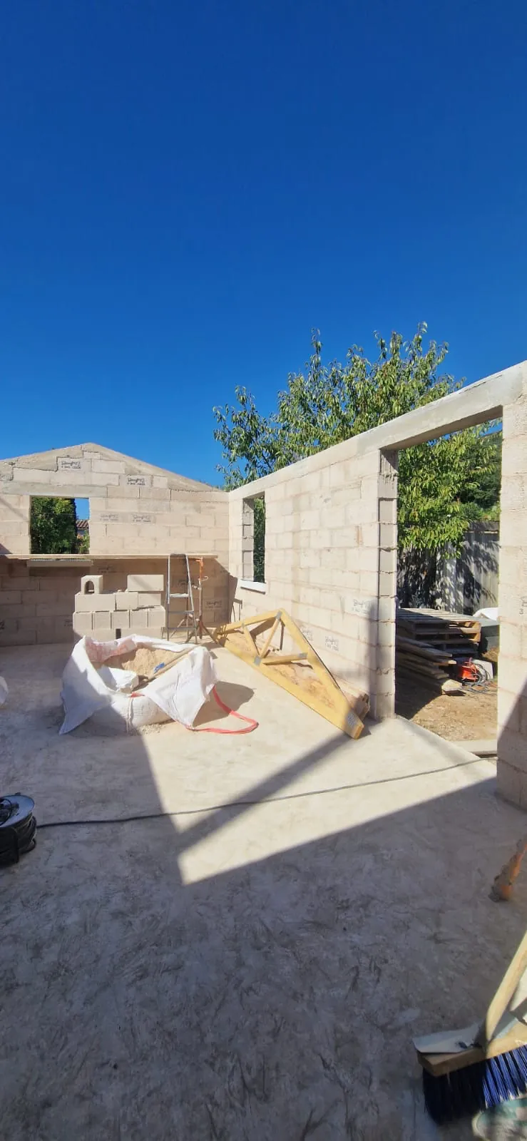 Élévation de murs en blocs de béton cellulaire sur une dalle, avec ouvertures et linteaux en place, sur un chantier au Val